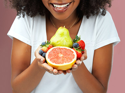 Buy stock photo Cropped studio shot of an young woman holding fruit against a pink background