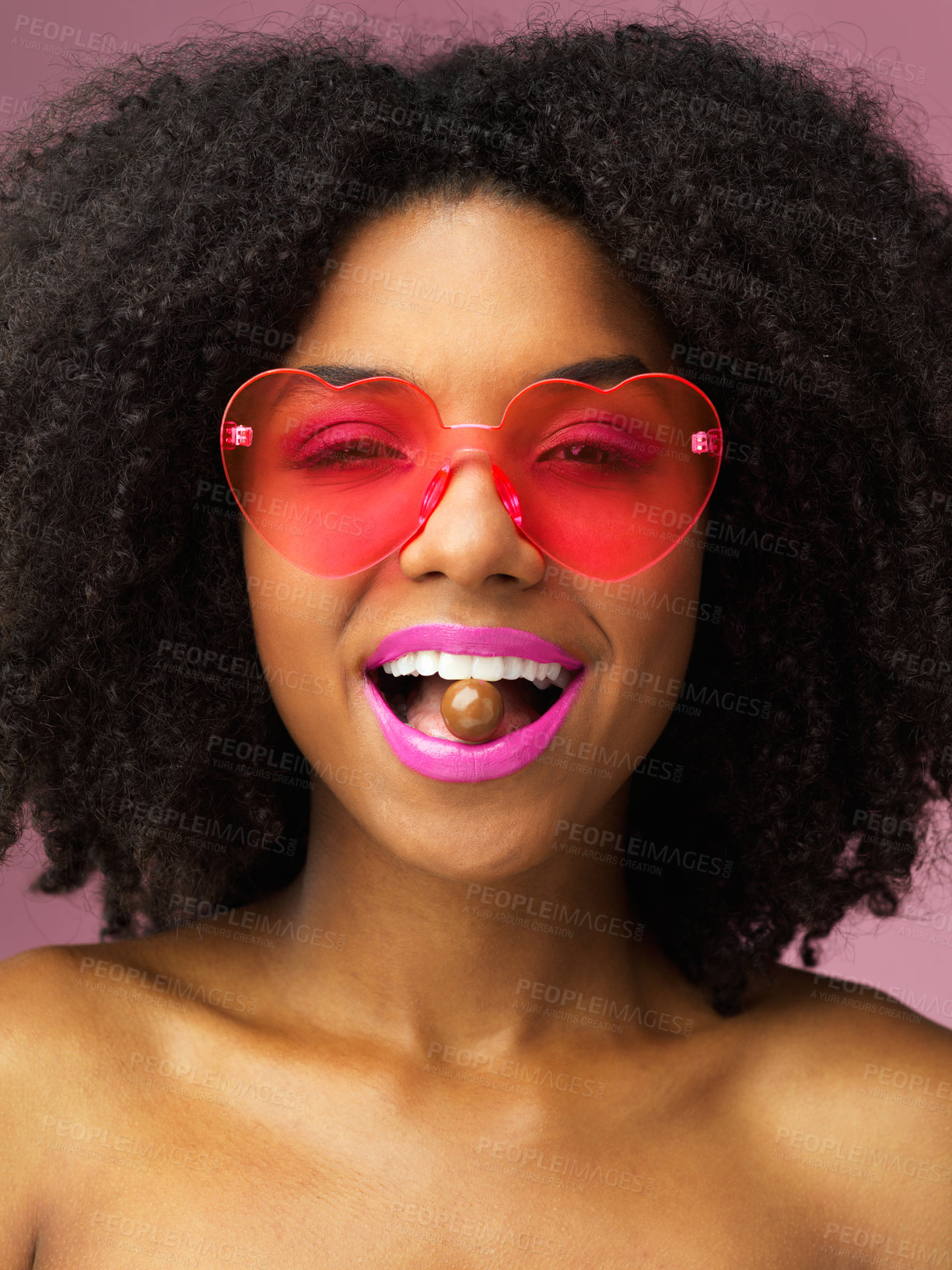 Buy stock photo Studio shot of an attractive young woman biting a chocolate against a pink background