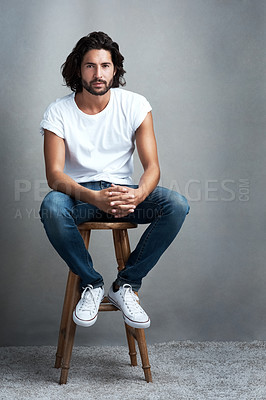 Buy stock photo Fashion, serious and portrait of man in studio on a stool with casual, cool and stylish outfit. Confidence, handsome and young male model from Mexico with trendy style on chair by gray background.