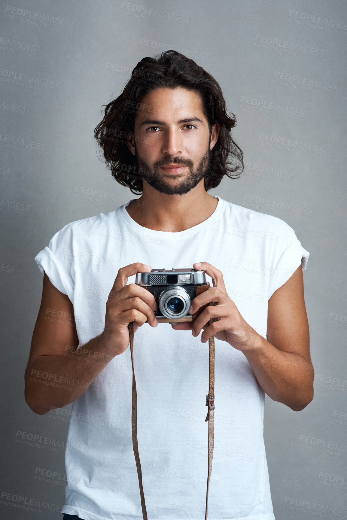 Buy stock photo Studio portrait of a young man posing with a vintage camera against a grey background
