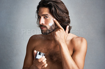 Buy stock photo Portrait, skincare or lotion with the face of a man in studio on a gray background for his grooming routine. Beauty, facial and a handsome or shirtless young person with antiaging cream for his skin