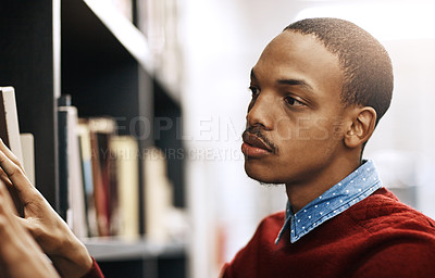 Buy stock photo Shot of a university student looking for a book in the library at campus