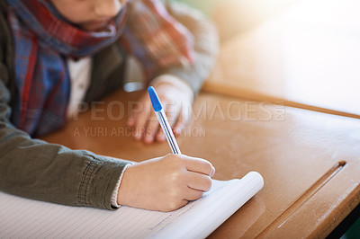 Buy stock photo Cropped shot of an unrecognizable elementary school girl writing in a workbook in the classroom