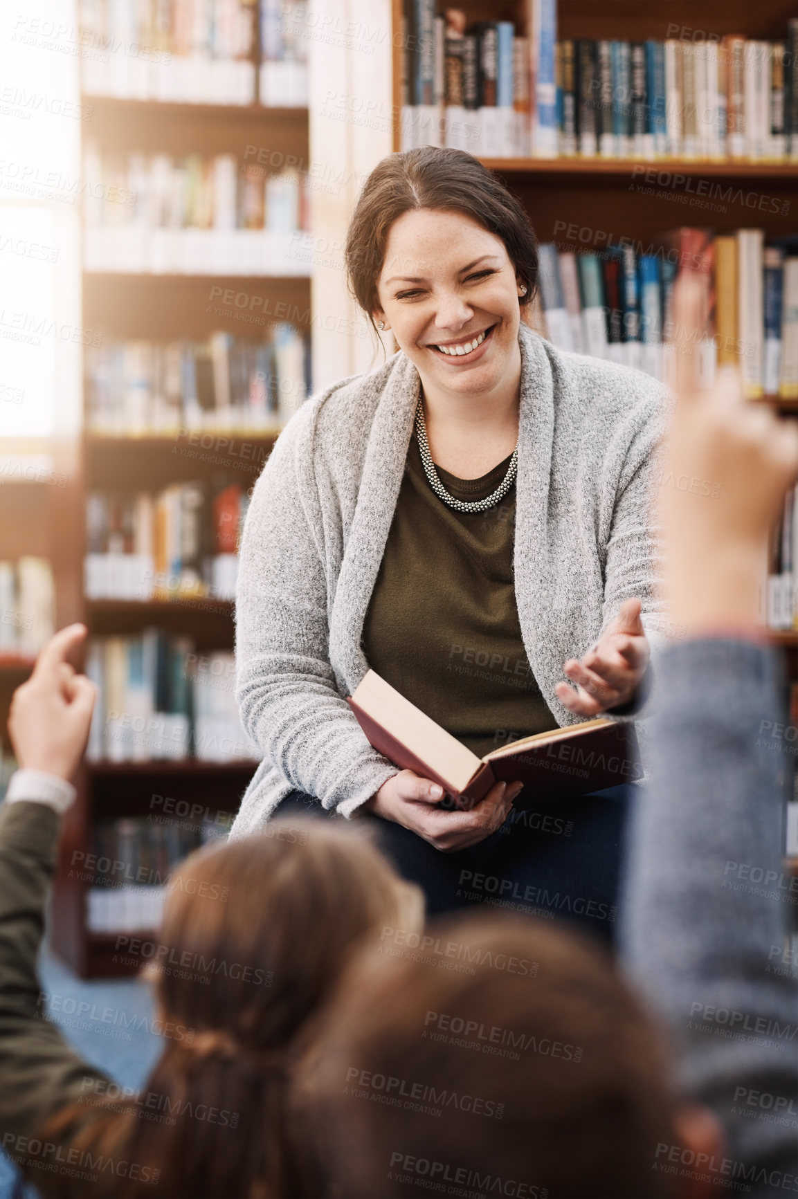 Buy stock photo Happy woman, teacher and children with question in library for storytelling, lesson or book test at school. Young, female person or story teller with hands raised for answer, interaction or youth