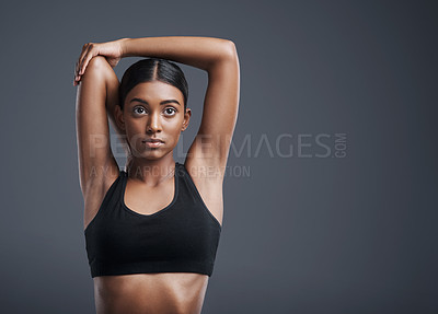 Buy stock photo Focus, mockup and stretching with an athlete woman in studio on a gray background for fitness or health. Exercise, mindset and warm up with an attractive young female model training her body