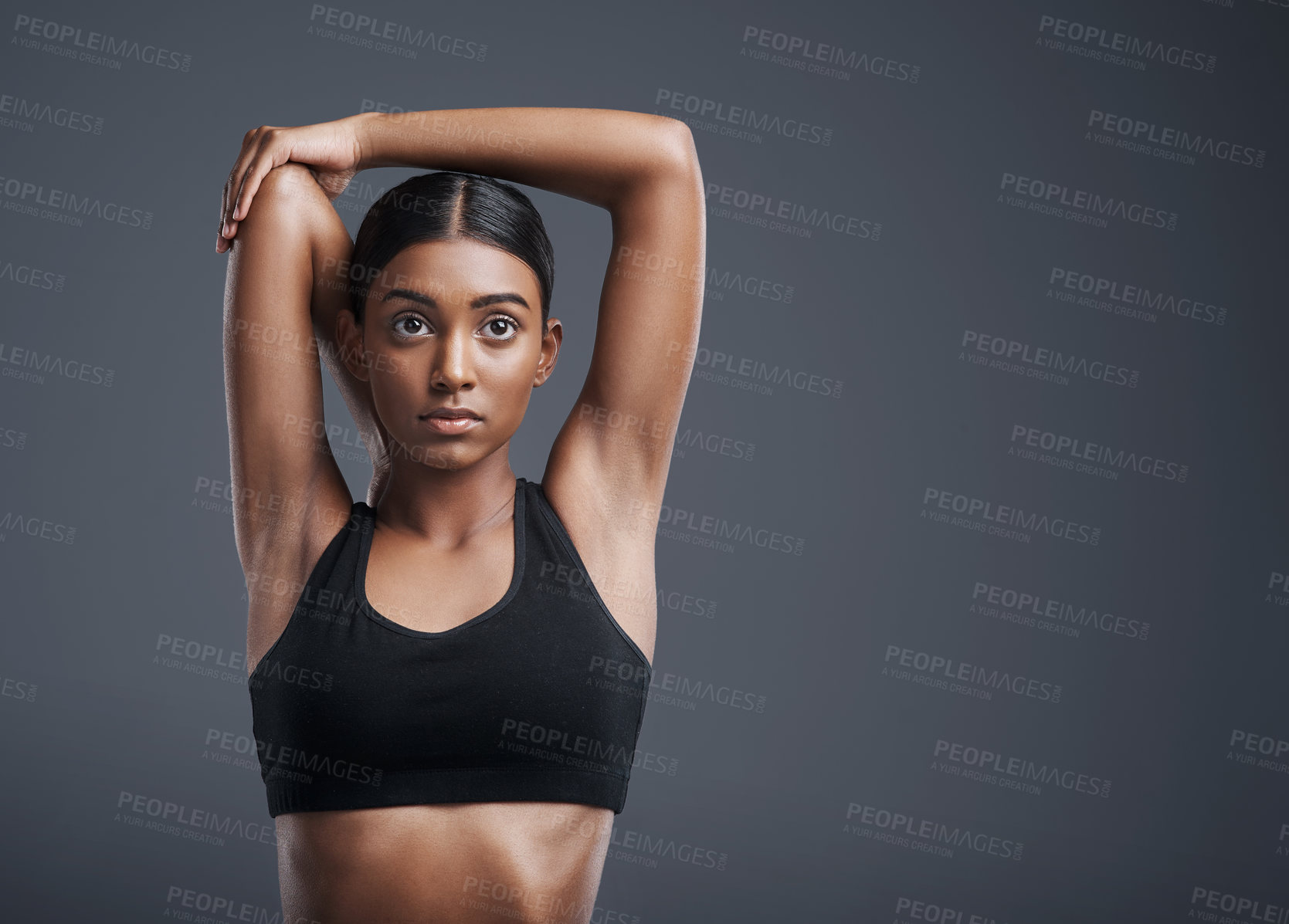 Buy stock photo Focus, mockup and stretching with an athlete woman in studio on a gray background for fitness or health. Exercise, mindset and warm up with an attractive young female model training her body