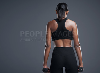 Buy stock photo Studio shot of a sporty young woman lifting weights against a grey background