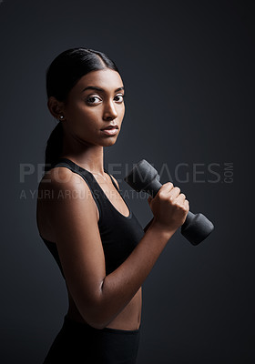 Buy stock photo Studio portrait of a young sportswoman doing dumbbell exercises against a gray background