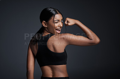 Buy stock photo Studio portrait of a young sportswoman flexing her bicep with her back turned to the camera against a gray background