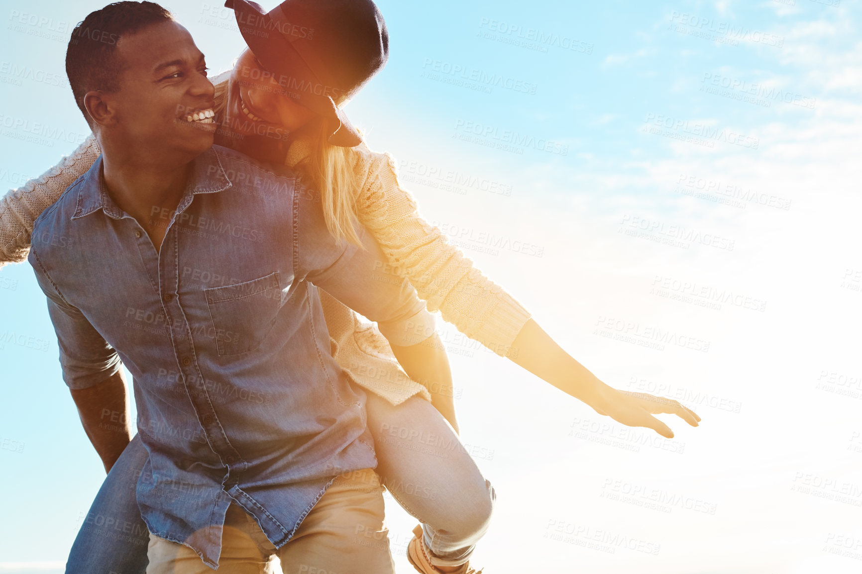 Buy stock photo Shot of a happy young couple enjoying a piggyback ride outdoors