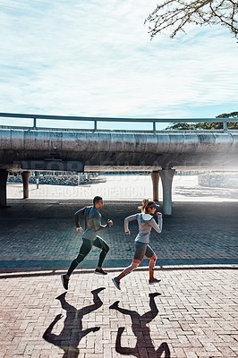 Buy stock photo Full length shot of two young and athletic young people running through the city