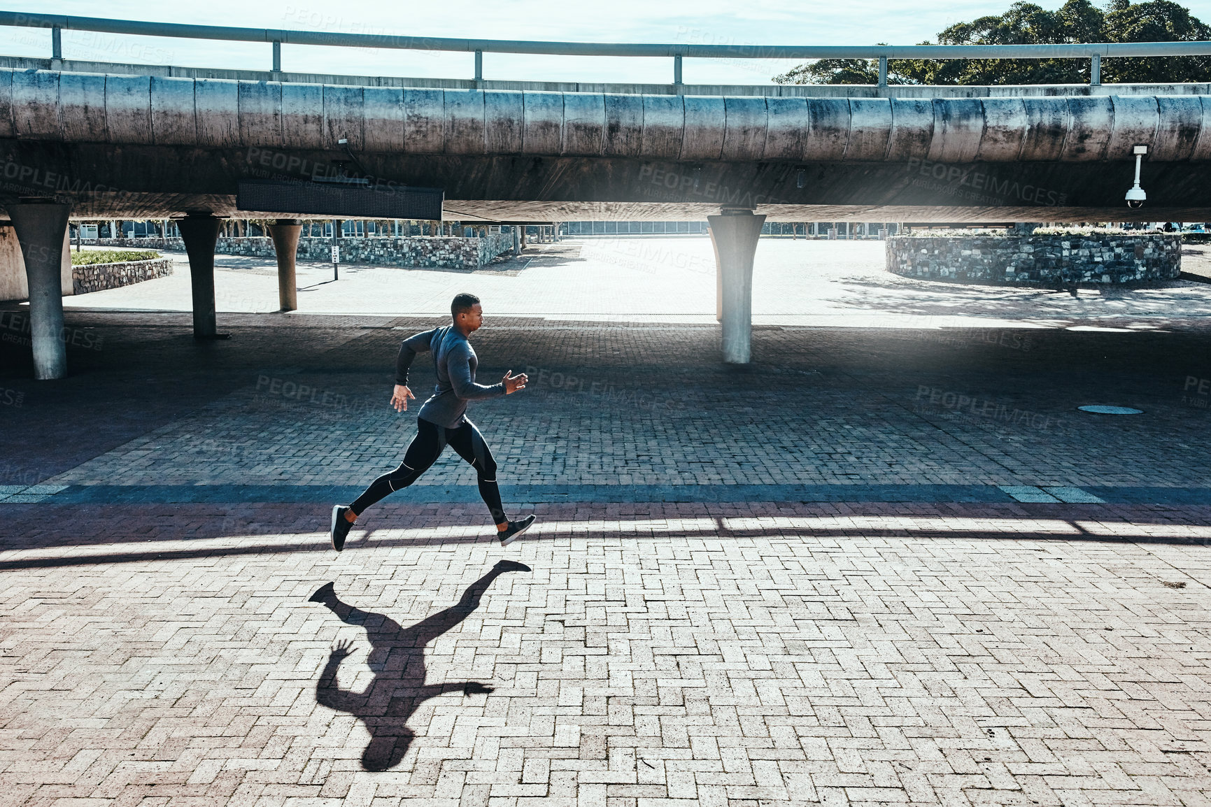 Buy stock photo Full length shot of a handsome and athletic young man running through the city