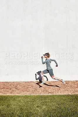 Buy stock photo Full length shot of an attractive and athletic young woman running on a path through the park