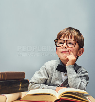 Buy stock photo Studio shot of a smart little boy reading books and looking thoughtful against a gray background