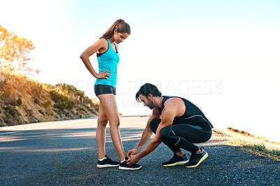 Buy stock photo Full length shot of a handsome young man tying his girlfriend's laces while out for a run