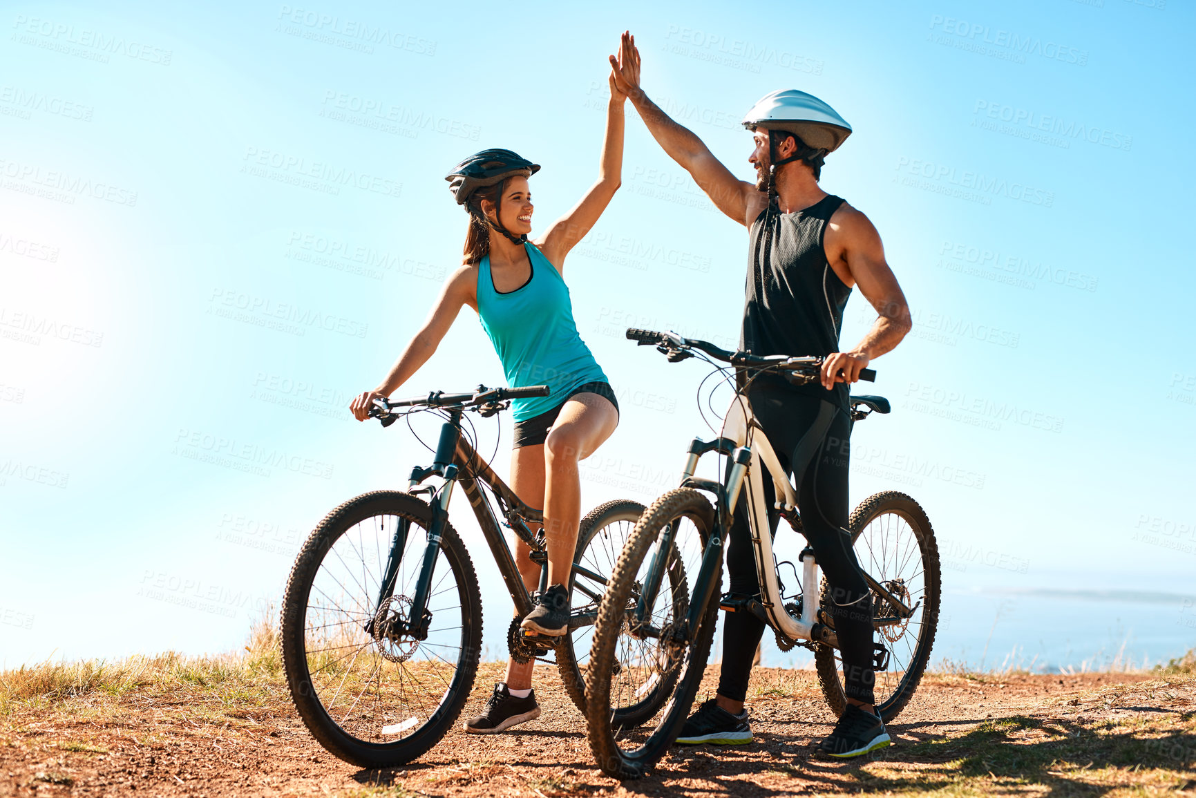 Buy stock photo Full length shot of a happy young couple high fiving while out mountain biking together