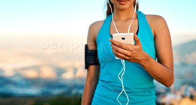 Buy stock photo Cropped shot of an unrecognizable young woman listening to music while out for a run