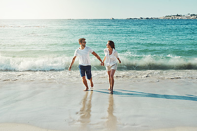 Buy stock photo Full length shot of a happy young couple running along the beach