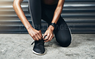 Buy stock photo Closeup shot of a sporty woman tying her shoelaces while exercising against a grey background