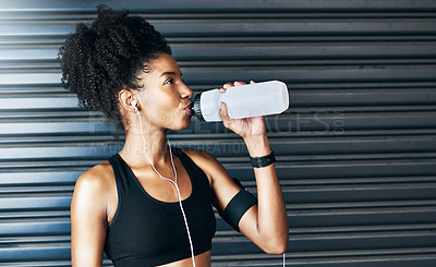 Buy stock photo Shot of a sporty young woman drinking water while exercising against a grey background