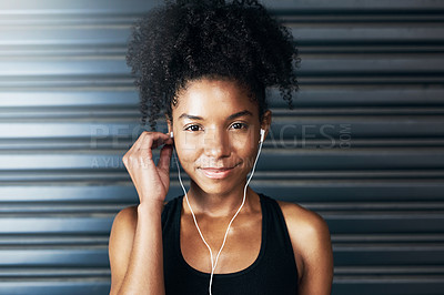 Buy stock photo Portrait of a sporty young woman listening to music while exercising against a grey background