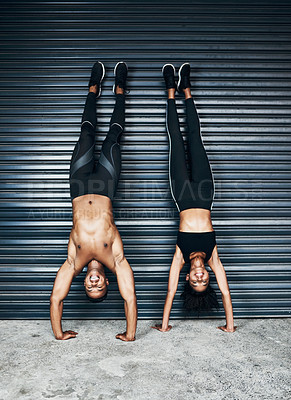 Buy stock photo Shot of a sporty young couple doing handstands against a grey background