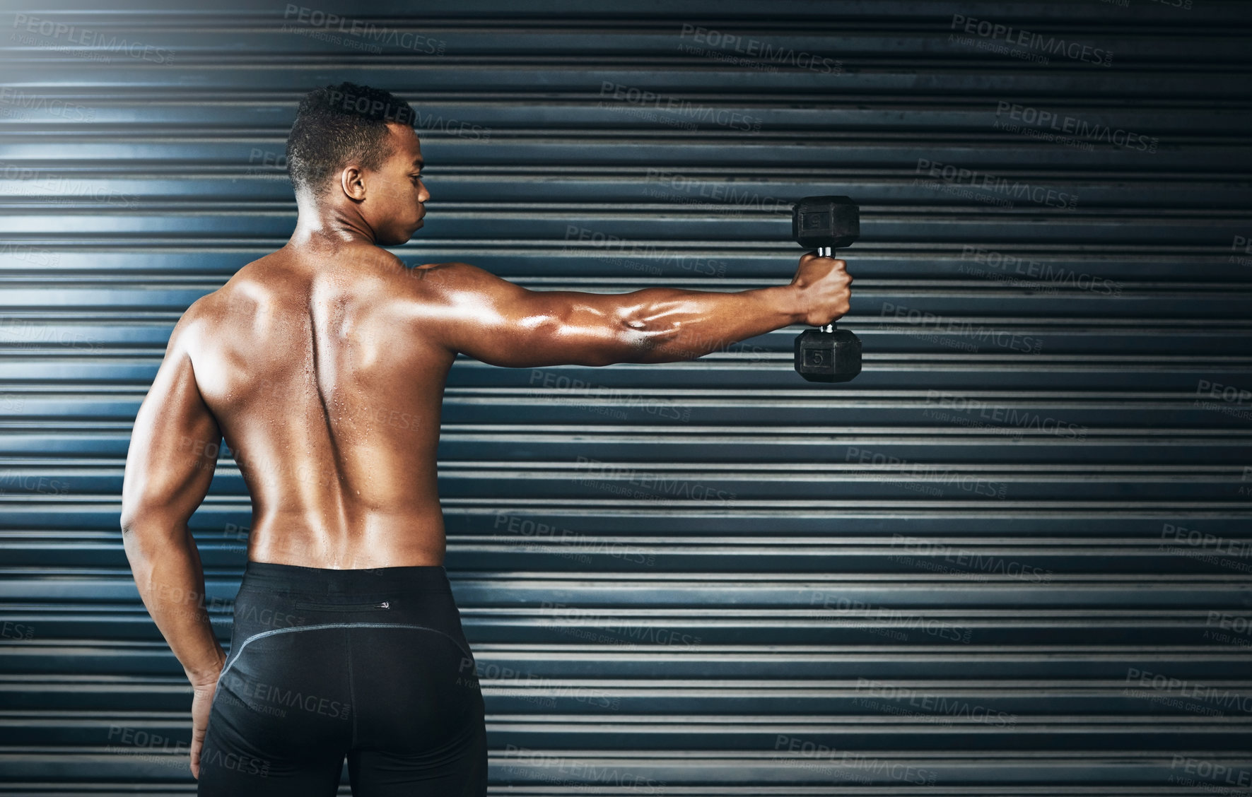 Buy stock photo Rearview shot of a muscular young man lifting weights against a grey background