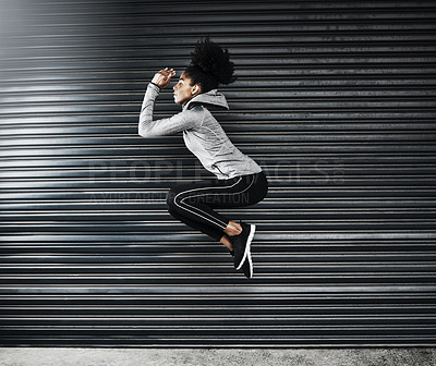 Buy stock photo Shot of a sporty young woman jumping against a grey background