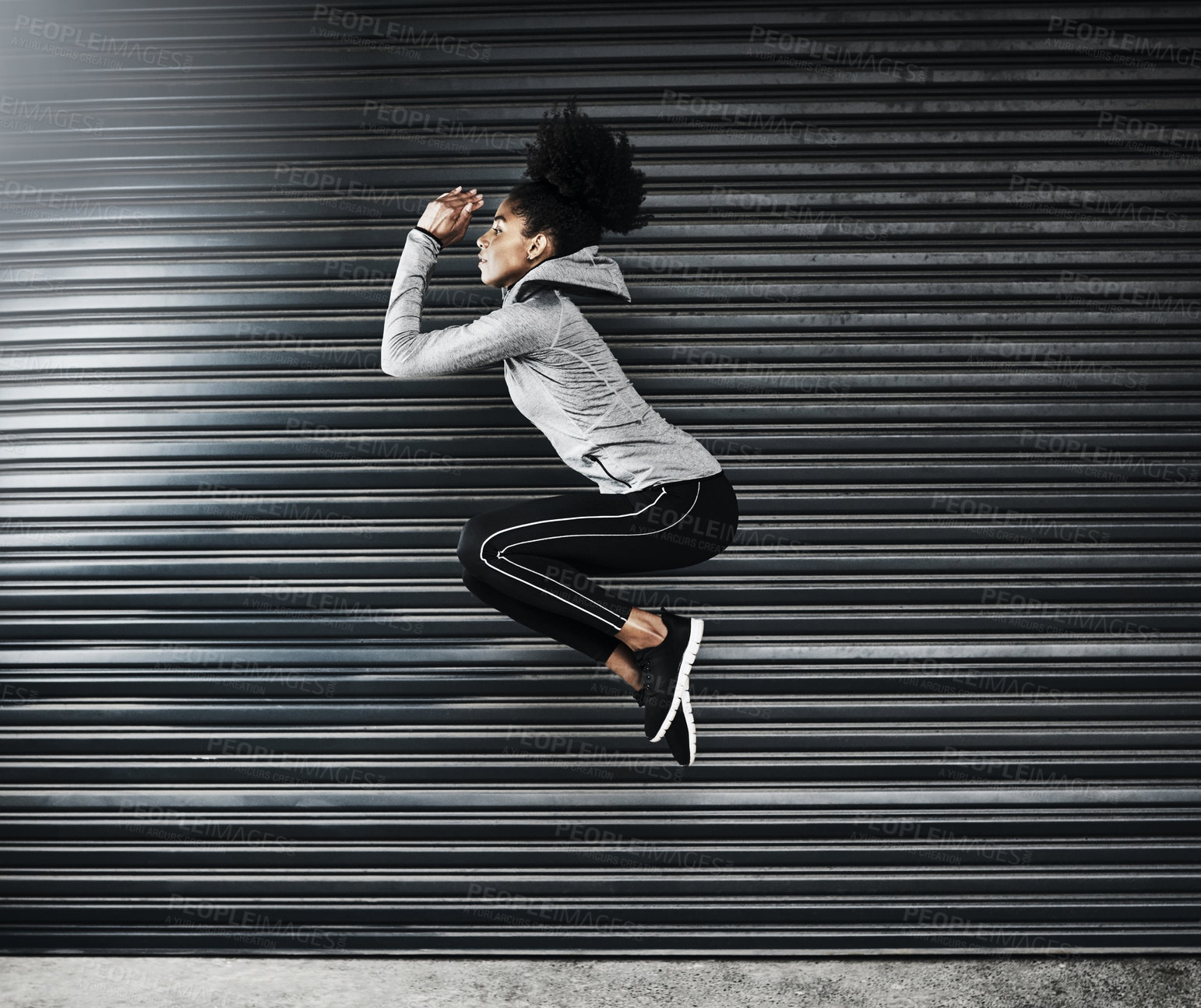 Buy stock photo Shot of a sporty young woman jumping against a grey background