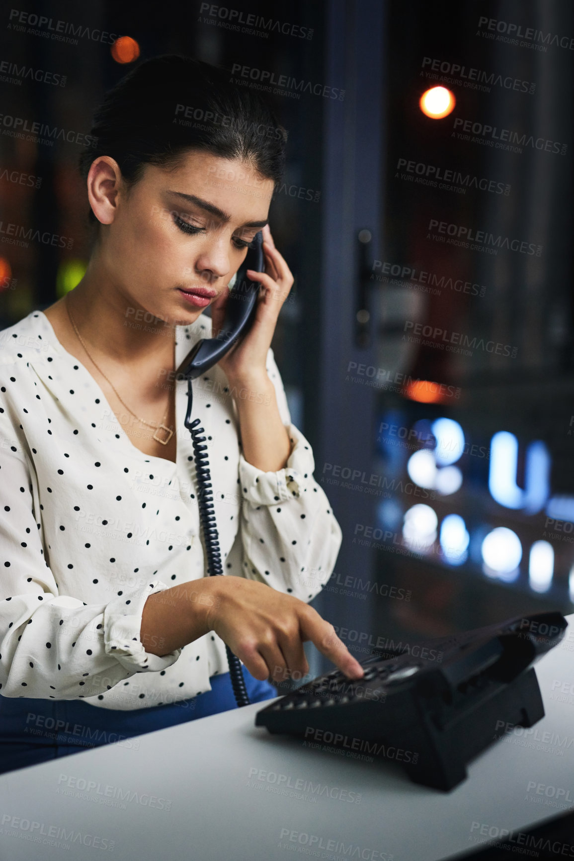 Buy stock photo Cropped shot of an attractive young businesswoman making a phonecall while working late in her office