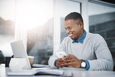 Buy stock photo Shot of a handsome young businessman using a cellphone and laptop while working in an office