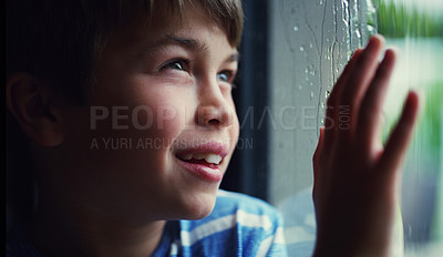 Buy stock photo Child, window and smile at rain drops or thinking in home with cold weather, thoughts or future. Male person, boy and hand or contemplating in winter for decision or wondering, youth or daydreaming