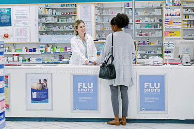 Buy stock photo Rearview shot of a young woman purchasing over the counter medication from a female pharmacist