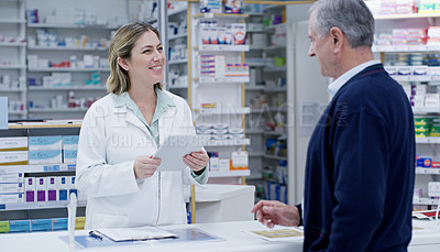 Buy stock photo Shot of a young pharmacist handing out a prescription to a senior citizen at a pharmacy