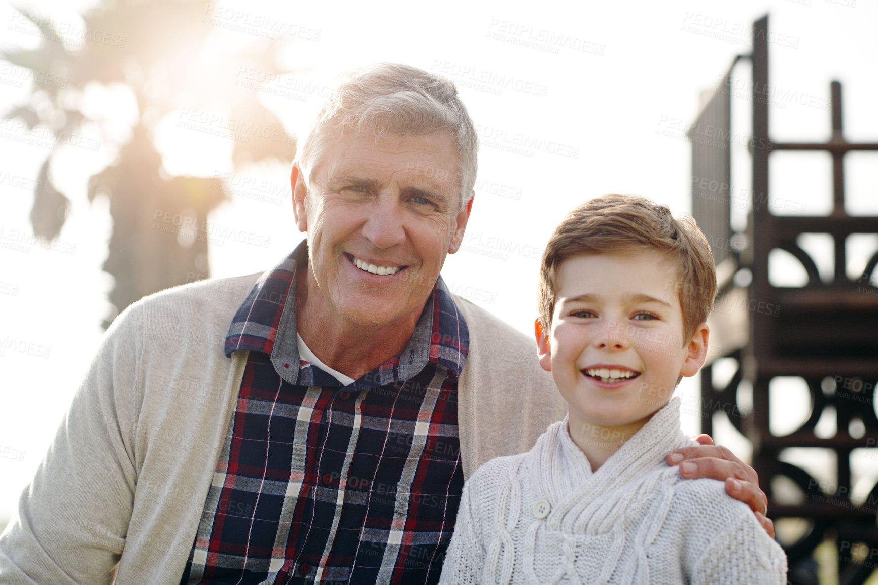 Buy stock photo Portrait of an adorable little boy posing with his grandfather while relaxing outdoors