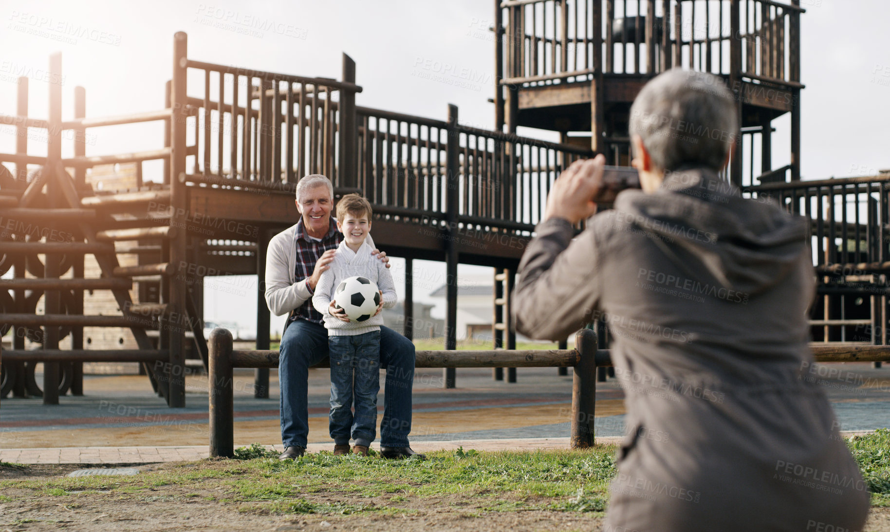 Buy stock photo Grandparents, child and cellphone picture at park for bonding with soccer ball, playground and photography. Person, back and smartphone photo for family memory or social media, post or online