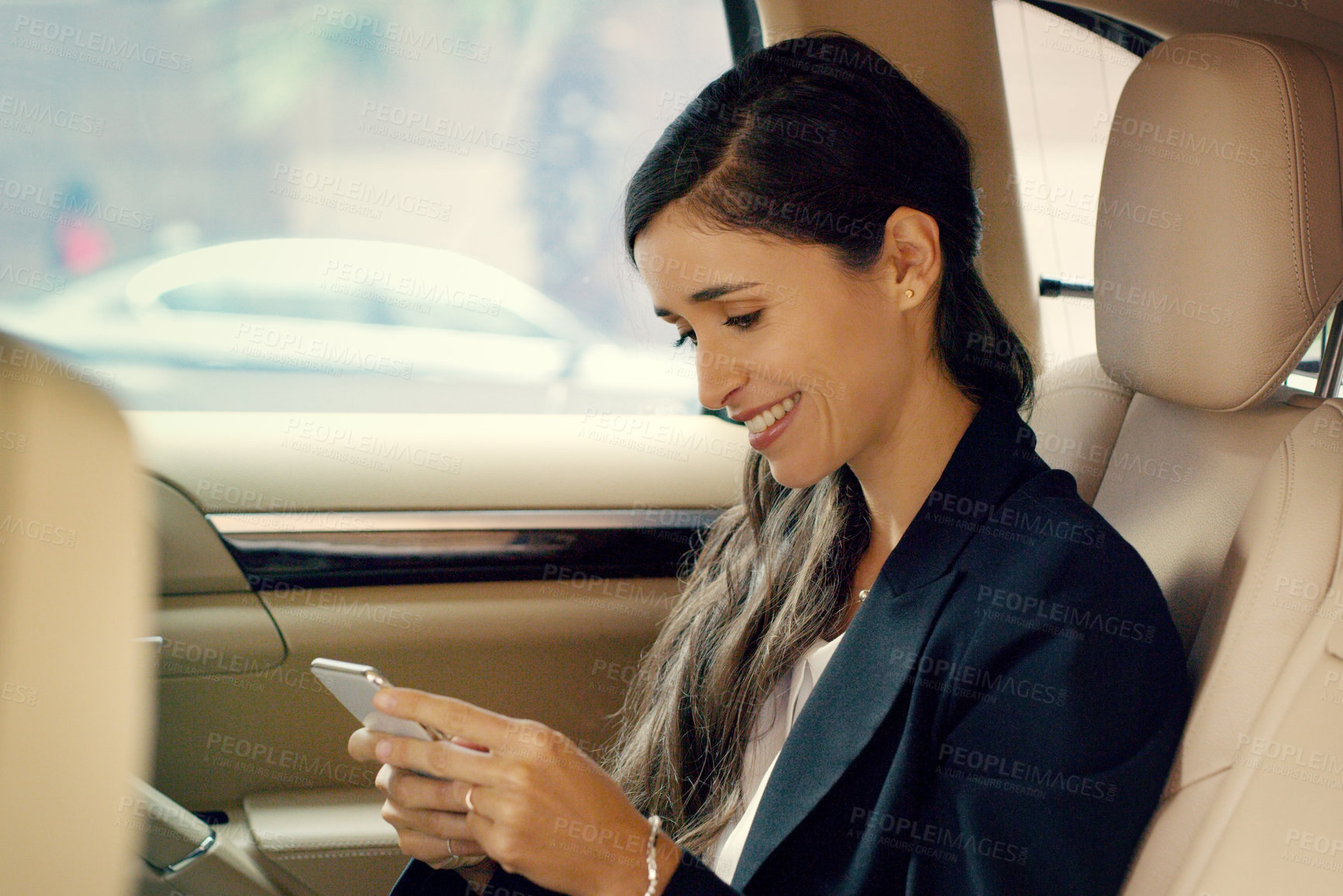 Buy stock photo Shot of an attractive young businesswoman using her cellphone inside a car while traveling to work