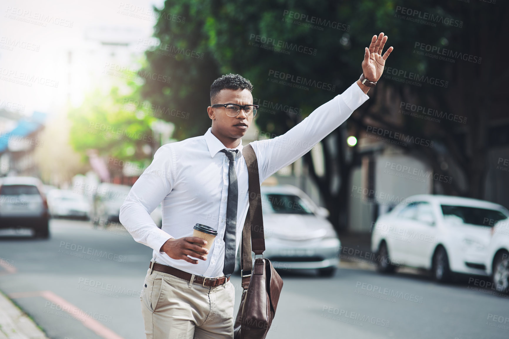 Buy stock photo Shot of a young businessman gesturing to get a cab in the city