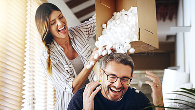 Buy stock photo Moving house, real estate and box with a crazy married couple having fun while playing in their new home together. Property, comic or foam with a playful husband and wife joking in the living room