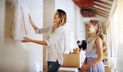 Buy stock photo Shot of a mother and her daughter deciding where to hang a frame in their new house