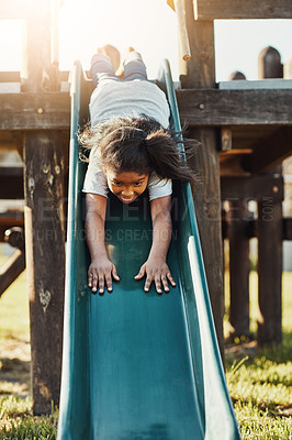 Buy stock photo Cropped shot of an adorable little girl playing on the slide at the park