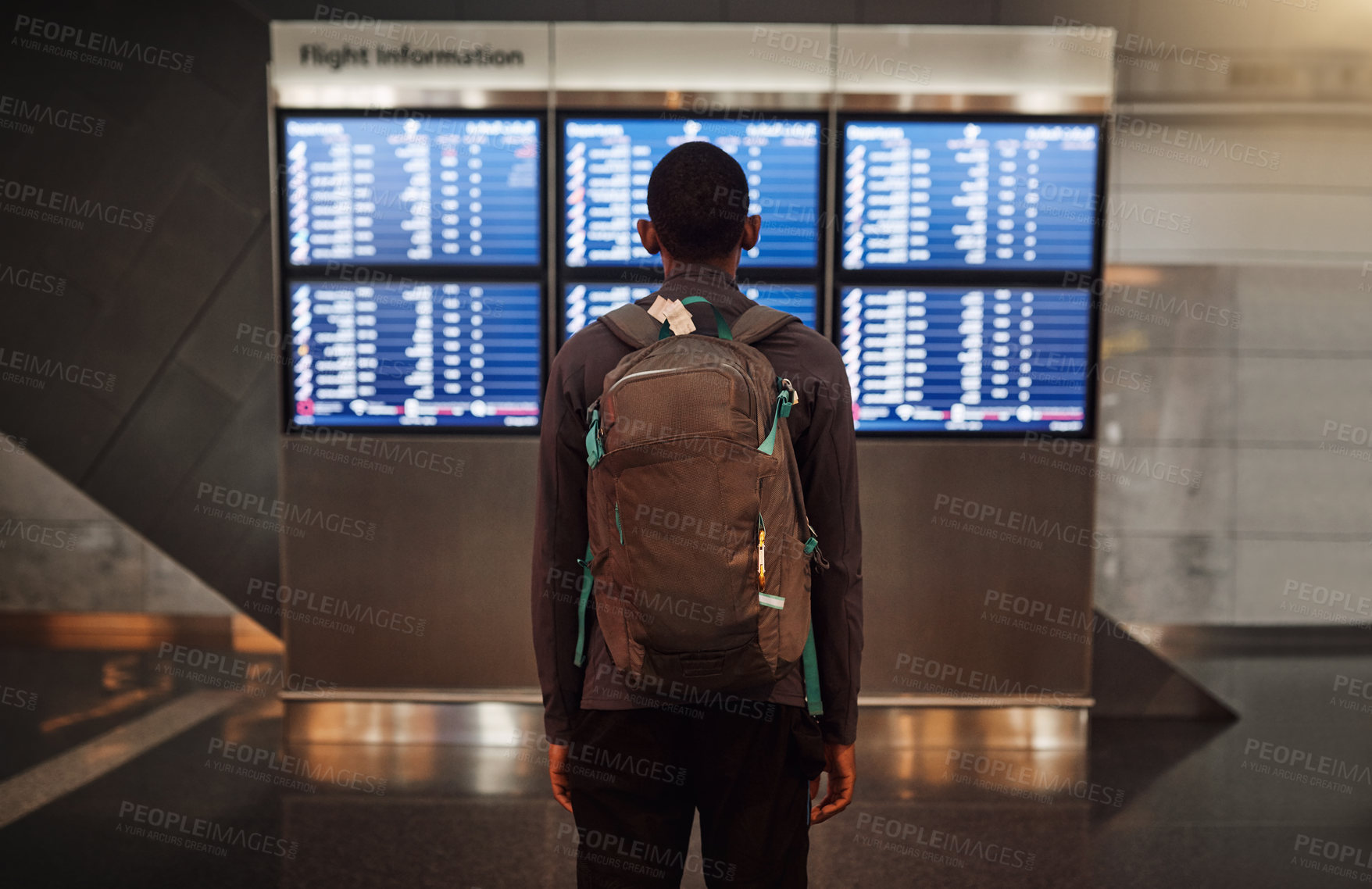 Buy stock photo Rearview shot of an unrecognizable young man checking the flight times in an airport