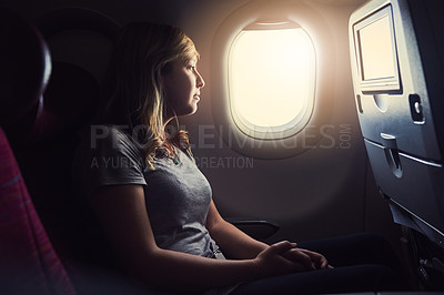 Buy stock photo Cropped shot of an attractive young woman looking through the window in an airplane