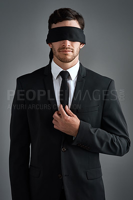 Buy stock photo Studio shot of a young businessman wearing a blindfold against a gray background
