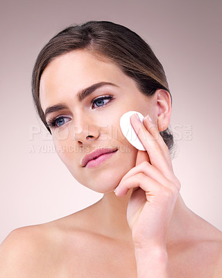 Buy stock photo Studio shot of an attractive young woman using a cotton pad on her face against a pink background