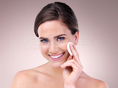 Buy stock photo Studio portrait of an attractive young woman using a cotton pad on her face against a pink background