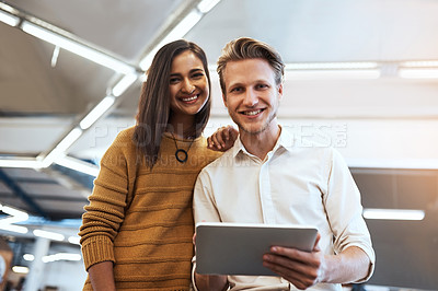Buy stock photo Cropped portrait of two young businesspeople looking at a tablet in their office