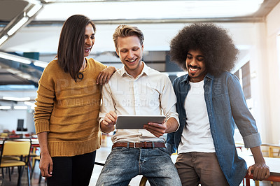 Buy stock photo Cropped shot of three young businesspeople looking at a tablet in their office