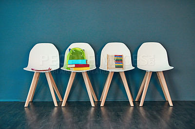 Buy stock photo Studio shot of a row of chairs with books and other learning material on them against a blue background