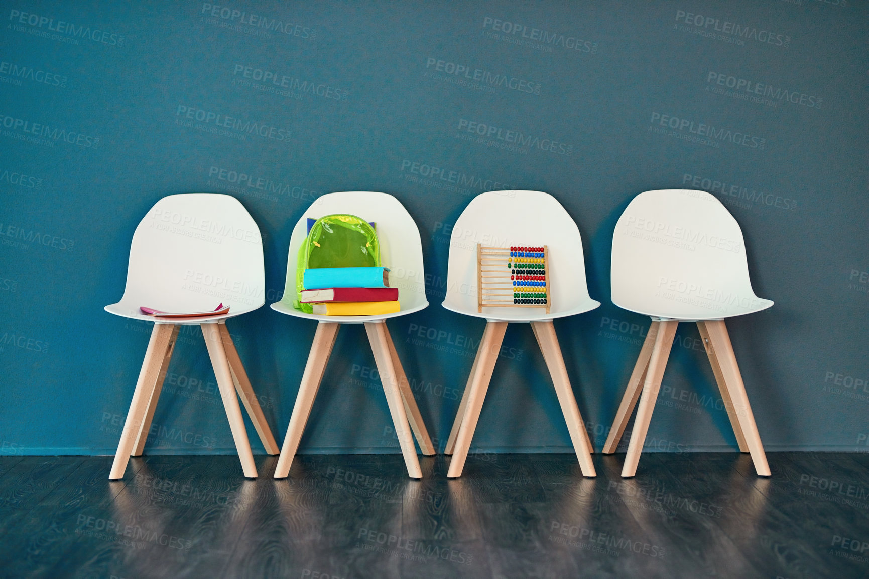 Buy stock photo Studio shot of a row of chairs with books and other learning material on them against a blue background